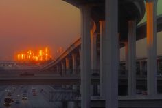 the sun is setting on an overpass with cars driving down it and buildings in the background