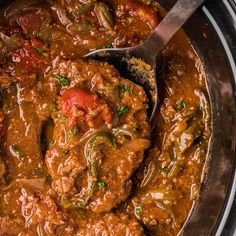 a close up of a stew in a crock pot with a ladle scooping out