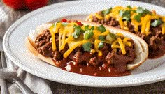 two chili cheese dogs on a white plate