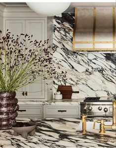 a kitchen with marble counter tops and gold accents on the hood, oven, stove top and cabinets