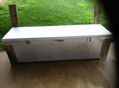 a metal box sitting on top of a wooden bench in front of a grassy field