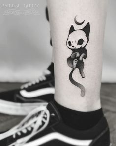 a black and white cat tattoo on the right leg with a crescent moon behind it