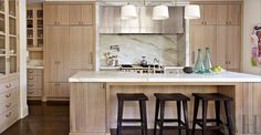 a modern kitchen with wooden cabinets and stainless steel appliances, along with bar stools