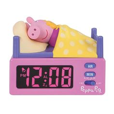 a pink alarm clock with a pig sleeping on it's back in a yellow dress