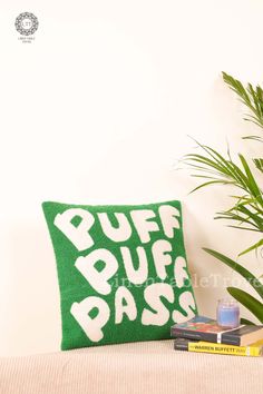 a green pillow sitting on top of a bed next to a book and potted plant