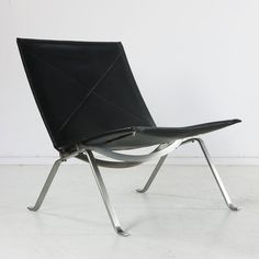 a black leather chair sitting on top of a white floor next to a metal frame