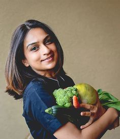 a woman holding a bunch of vegetables in her hands