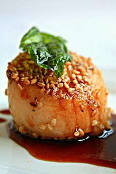 a piece of meat with sauce and green leaf on top is sitting on a plate