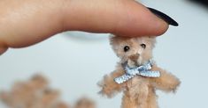 a person holding a tiny teddy bear in their hand