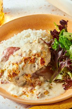 a plate topped with meat covered in gravy next to rice and a salad