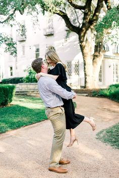 an engaged couple embrace in front of a large tree