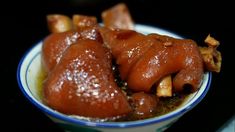 two pieces of meat in a bowl with sauce on the top and some bread sticks sticking out of it