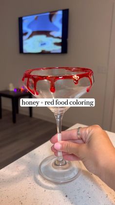 a person is holding a wine glass with red liquid on it and the words honey - red food coloring