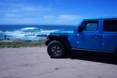 a blue jeep parked on top of a sandy beach