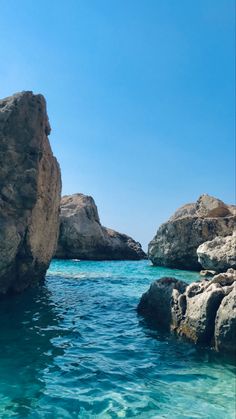 the water is crystal blue and there are large rocks in the ocean next to it