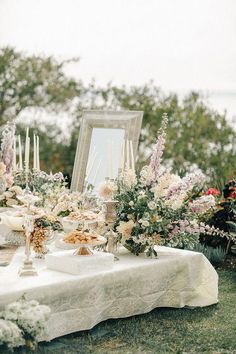 a table topped with flowers and candles next to a mirror