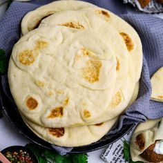 several pita breads in a pan on top of a table with other food items