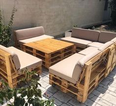 an outdoor furniture set made out of pallets and wooden planks is sitting on a brick patio