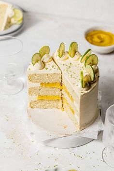 there is a cake that has been cut into pieces and sits on the table next to glasses