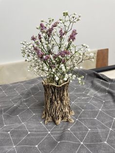 a vase filled with white and purple flowers on top of a black tablecloth covered table