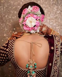 the back of a woman's head with flowers in her hair and jewelry on it