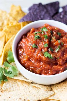 a white bowl filled with salsa surrounded by tortilla chips