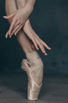 a ballerina's feet with her hands on the ballet shoe