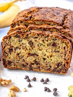 a loaf of chocolate chip banana bread sitting on top of a white counter next to bananas