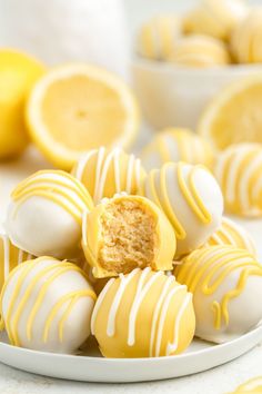 a white plate topped with yellow and white chocolate covered candies next to lemons