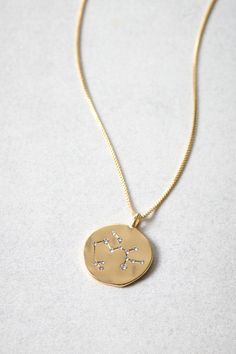 the zodiac sign necklace is gold and has white diamonds set in it's center