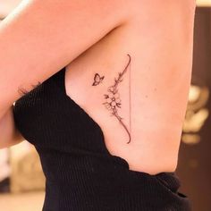 a woman with a butterfly tattoo on her upper arm and lower back shoulder, holding a flower