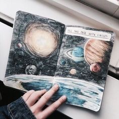 someone is holding an open book with pictures of the planets on it and pointing at them