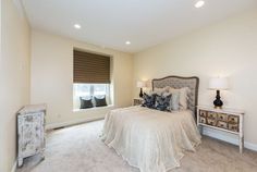 a bedroom with white walls and carpeted flooring has a bed, nightstands, and window