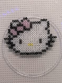 a hello kitty beaded brooch sitting on top of a glass plate