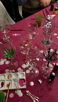 the table is covered with wine glasses and other crafting supplies