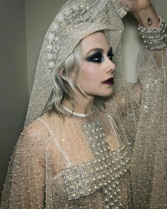 a woman with white hair and makeup wearing a veil over her head is posing for the camera