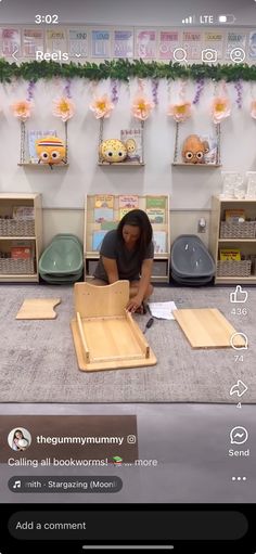 a woman is sitting on the floor in front of some wooden boxes and looking at her phone