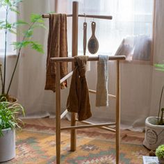 a rack with towels hanging on it in front of a window and potted plants