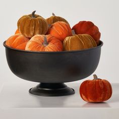 a black bowl filled with pumpkins on top of a table