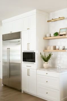 a kitchen with white cabinets, stainless steel refrigerator and open shelving above the stove