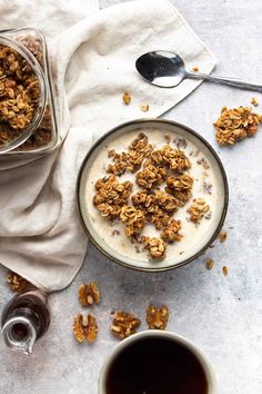 a bowl of granola next to a cup of coffee and spoons on a table