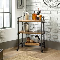 a kitchen cart with bottles and glasses on it in front of a white brick wall