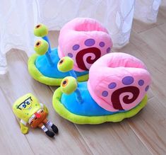 two children's slippers sitting on top of a wooden floor next to a toy