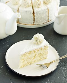 a piece of cake on a plate with a fork and tea pot in the background