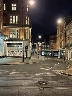 an empty city street at night with no cars or people on the road and buildings in the background