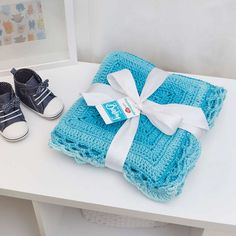 a blue blanket and pair of baby shoes on a white table