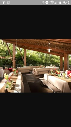 an outdoor dining area with tables, chairs and flowers in vases on the table