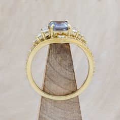 a yellow gold ring with three diamonds on top and a blue stone in the middle