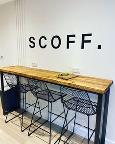 a wooden table sitting in front of a wall with scoff written on it