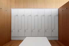 an empty room with several white lockers and wood flooring on either side of the room